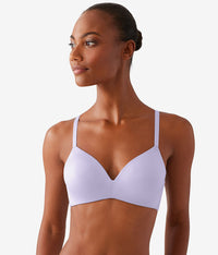 Woman wearing a white bra against a plain background